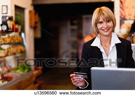 Stock Image - Businesswoman shopping online in cafe. Fotosearch