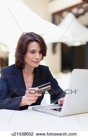 Stock Image - Businesswoman shopping online outdoors. Fotosearch