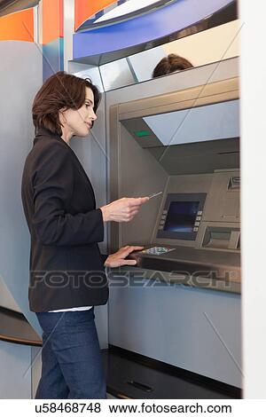 Stock Photo - Businesswoman using ATM outdoors. Fotosearch