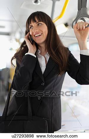 Stock Photo - Businesswoman using cell phone on bus. Fotosearch