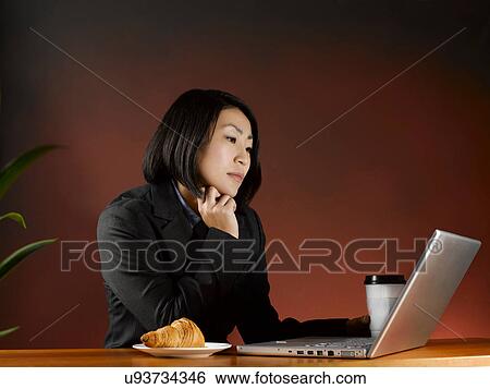Stock Photograph - Businesswoman using laptop at desk. Fotosearch