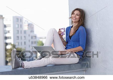 Businesswoman using laptop on balcony View Large Photo Image Stock Photograph - Businesswoman using laptop on balcony. Fotosearch