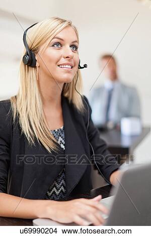 Businesswoman wearing headset at desk View Large Photo Image Picture - Businesswoman wearing headset at desk. Fotosearch