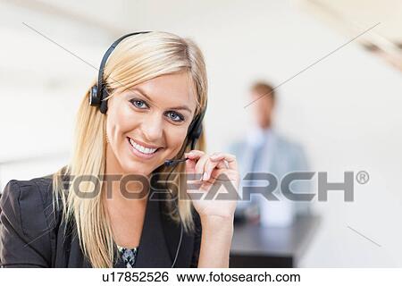 Businesswoman wearing headset at desk View Large Photo Image Stock Photograph - Businesswoman wearing headset at desk. Fotosearch