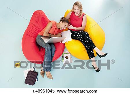 Businesswomen laughing in bean bags View Large Photo Image Stock Photography - Businesswomen laughing in bean bags. Fotosearch