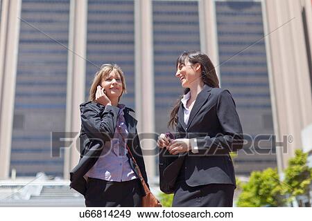 Stock Photo - Businesswomen on cell phone outdoors. Fotosearch