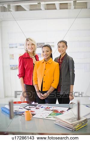 Stock Image - Businesswomen smiling in office. Fotosearch