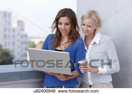 Businesswomen using laptop together View Large Photo Image Stock Photo - Businesswomen using laptop together. Fotosearch