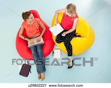 Stock Photo - Businesswomen working in bean bag chairs. Fotosearch