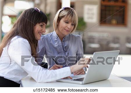 Stock Photography - Businesswomen working on laptop together. Fotosearch