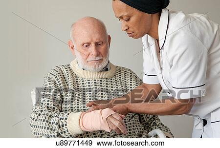 Stock Photo - Caretaker wrapping older man's wrist. Fotosearch