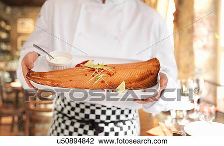 Stock Image - Chef in restaurant holding hot-smoked Scottish salmon. Fotosearch