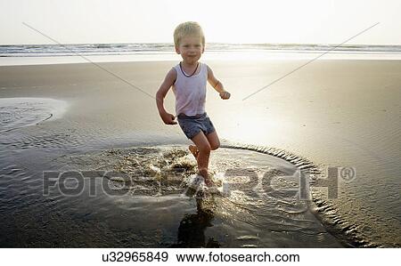 Stock Photo - Child playing in water at beach. Fotosearch