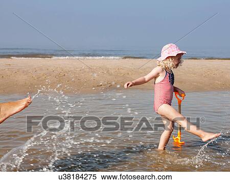 Stock Photography - Child playing in water at beach. Fotosearch