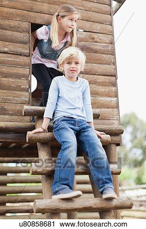 Stock Image - Children climbing out of playhouse. Fotosearch