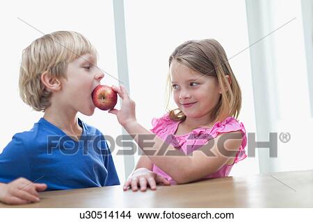Children eating apple in kitchen View Large Photo Image Picture - Children eating apple in kitchen. Fotosearch