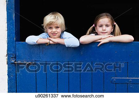 Stock Photo - Children leaning over barn door. Fotosearch
