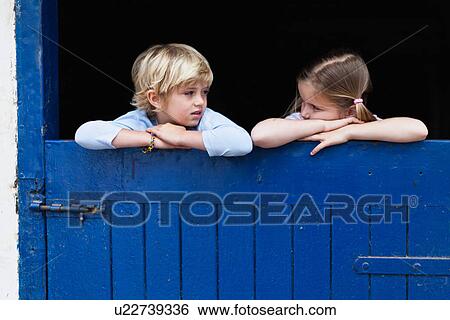 Stock Photograph - Children leaning over barn door. Fotosearch