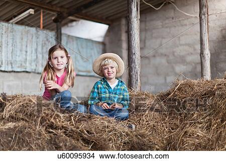 Picture - Children sitting in haystack in stable. Fotosearch