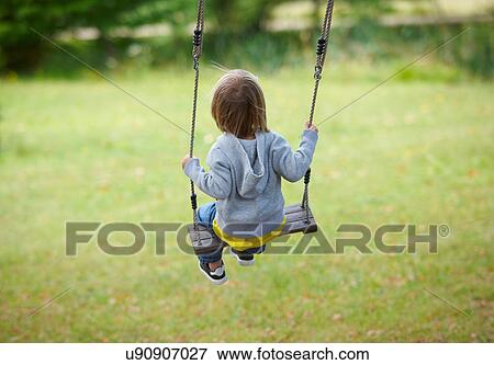 Stock Photo - Children sitting in swing in backyard. Fotosearch