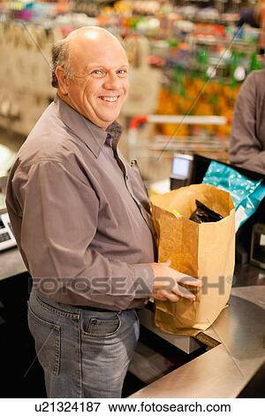 Clerk bagging groceries in store View Large Photo Image Stock Photo - Clerk bagging groceries in store. Fotosearch