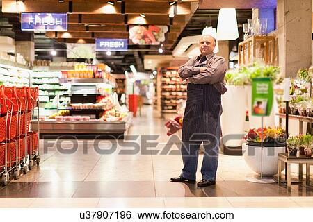 Clerk standing in grocery store View Large Photo Image Stock Photograph - Clerk standing in grocery store. Fotosearch