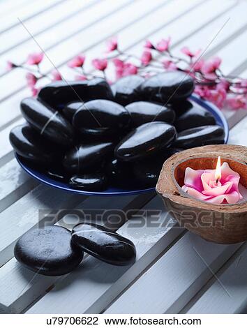 Stock Image - Close up of bowl of rocks and candle. Fotosearch