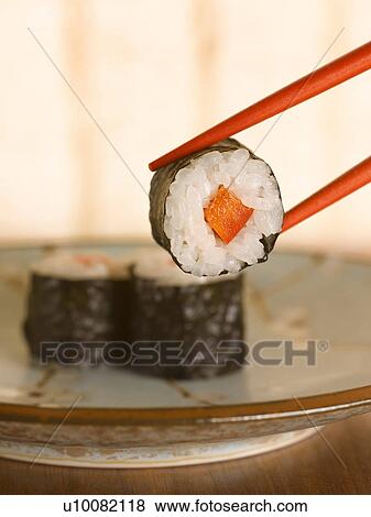 Close up of chopsticks holding sushi View Large Photo Image Stock Photo - Close up of chopsticks holding sushi. Fotosearch
