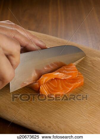 Stock Photography - Close up of hands chopping salmon. Fotosearch