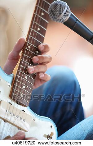 Stock Image - Close up of man playing guitar. Fotosearch