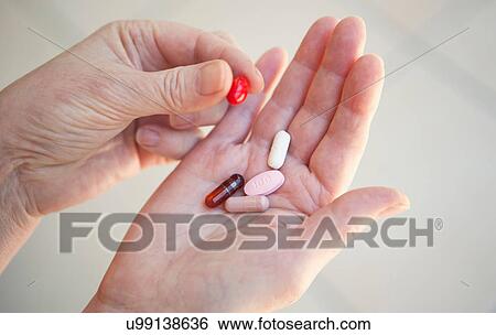 Stock Photograph - Close up of older person holding pills. Fotosearch