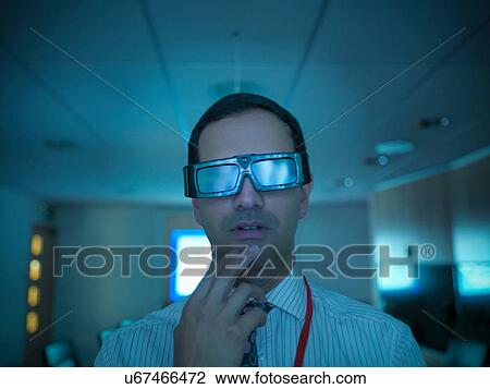 Stock Image - Close up of scientist wearing 3D glasses and looking at screen. Fotosearch