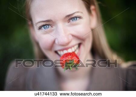 Stock Image - Close up of strawberry in woman's mouth. Fotosearch