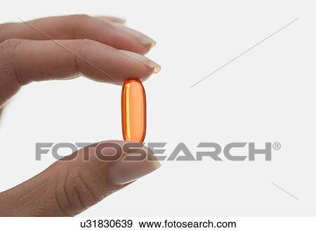 Stock Photo - Close up of woman holding pill. Fotosearch