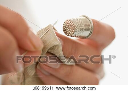 Stock Image - Close up of woman sewing with thimble. Fotosearch