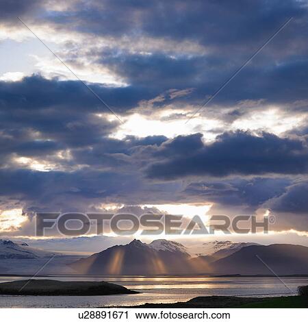 Stock Image - Clouds over mountains and lake. Fotosearch