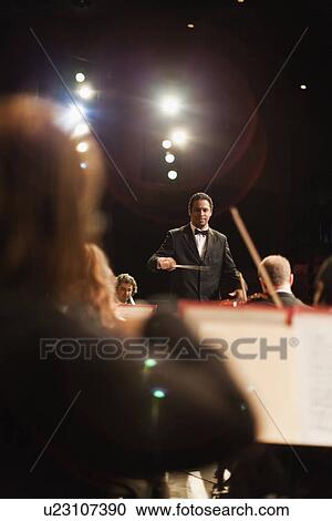 Stock Image - Conductor waving baton over orchestra. Fotosearch