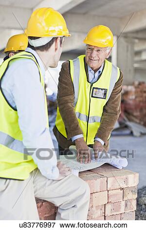 Stock Photo - Construction workers reading blueprints. Fotosearch