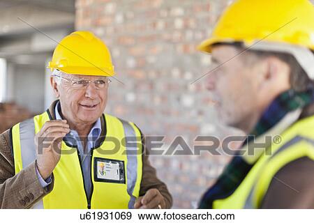 Construction workers talking on site View Large Photo Image Stock Photo - Construction workers talking on site. Fotosearch