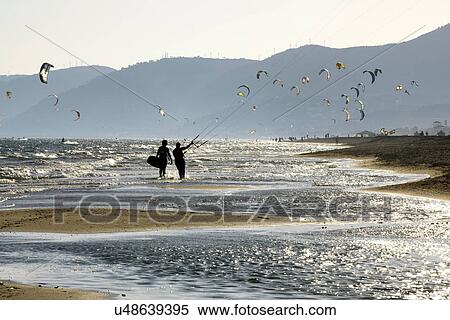 Stock Photography - Couple flying kites on beach. Fotosearch