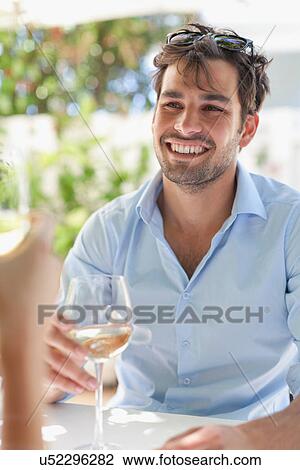 Stock Image - Couple having wine at table outdoors. Fotosearch