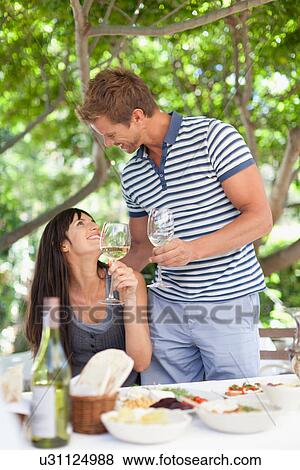 Stock Photo - Couple having wine at table outdoors. Fotosearch