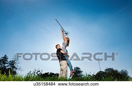 Couple holding up antenna outdoors View Large Photo Image Picture - Couple holding up antenna outdoors. Fotosearch