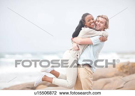Stock Image - Couple hugging on beach. Fotosearch