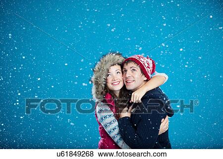 Stock Photo - Couple in hats hugging in snow. Fotosearch