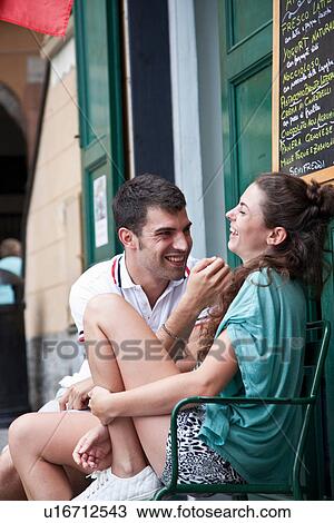 Stock Image - Couple laughing on city bench. Fotosearch