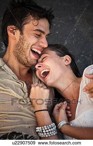 Couple laughing on sand at beach View Large Photo Image Stock Photo - Couple laughing on sand at beach. Fotosearch