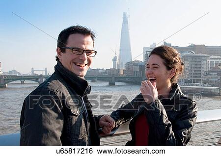 Stock Photograph - Couple laughing on urban bridge. Fotosearch