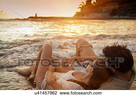 Couple laying on sand at beach View Large Photo Image Stock Image - Couple laying on sand at beach. Fotosearch