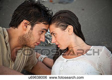 Stock Photograph - Couple laying on sand at beach. Fotosearch